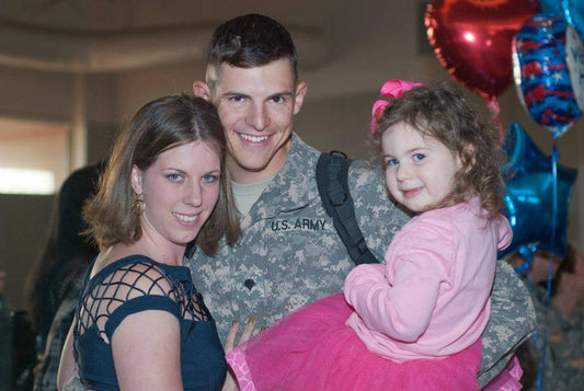 Full Boar Labs founder in Army uniform at deployment homecoming with wife and toddler daughter.